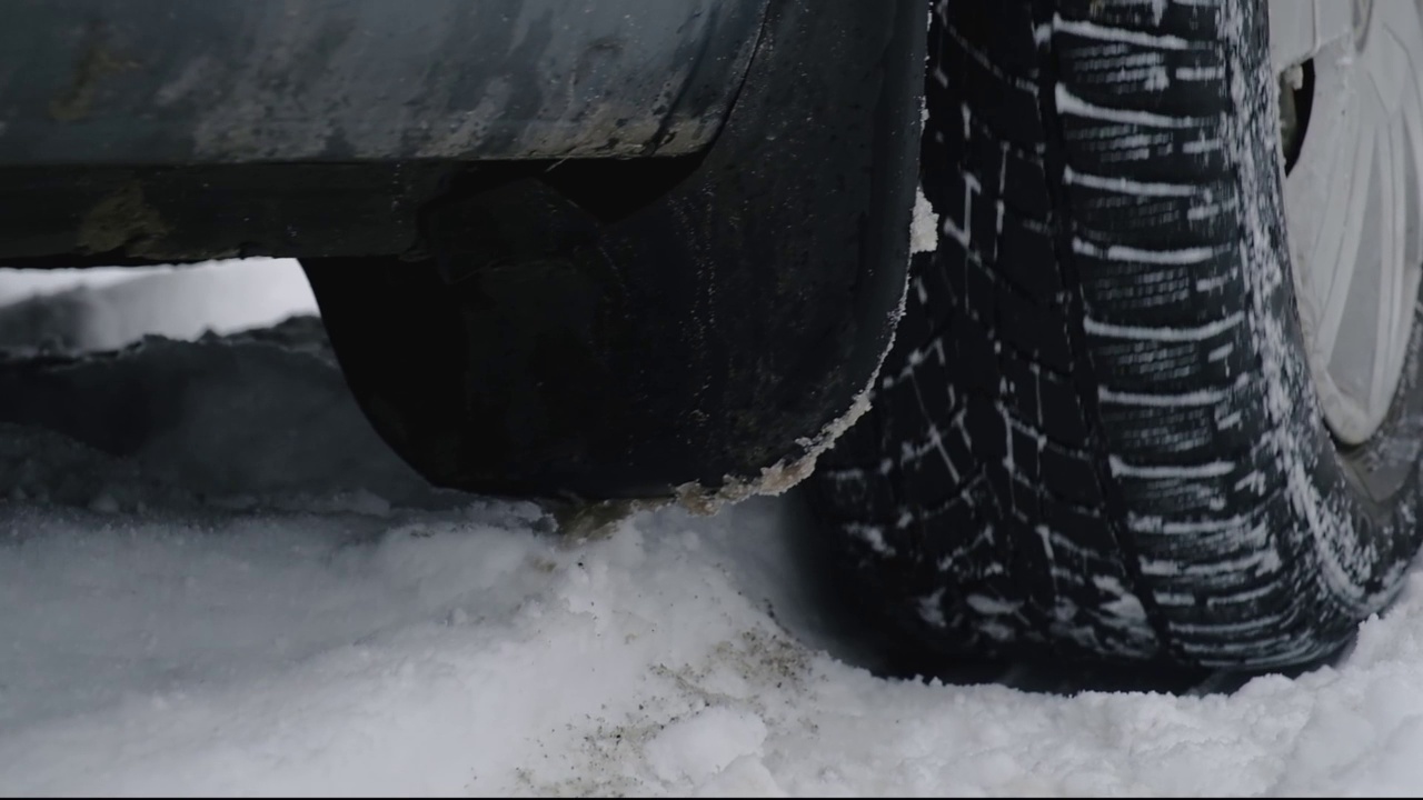 车在雪地里。轮胎在雪路上打滑。雪从汽车的纺车上飞升视频下载