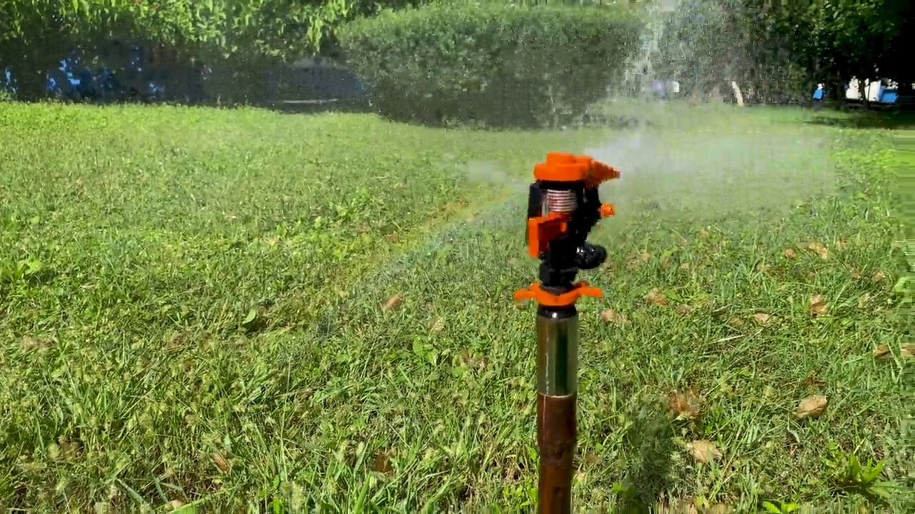 草坪自动洒水车，将水滴洒落在草坪的绿草上视频素材