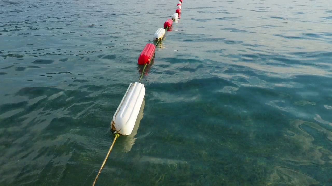 浮标游泳区标志。可见的通道标记涂有持久的白色和海洋红色珐琅增加耐久性。组装屏障和游泳区。水上浮标，亚得里亚海，黑山。视频素材