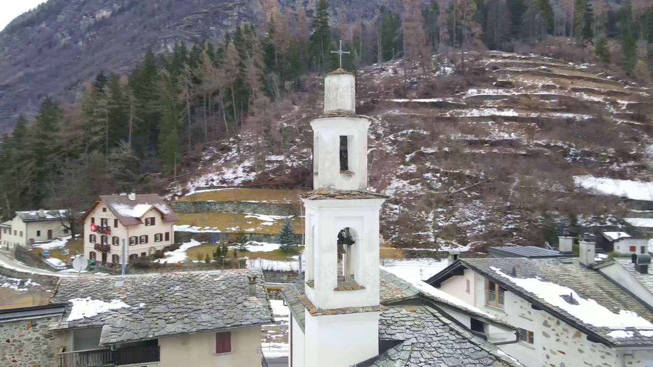 冬季美丽的瑞士阿尔卑斯山和建筑，无人机在群山中心的瑞士小村庄上空飞行，周围环绕着墨绿色的湖泊，古老的小屋，房屋和教堂，高塔映衬着令人惊叹的阿尔卑斯山背景，雪山倒影视频素材