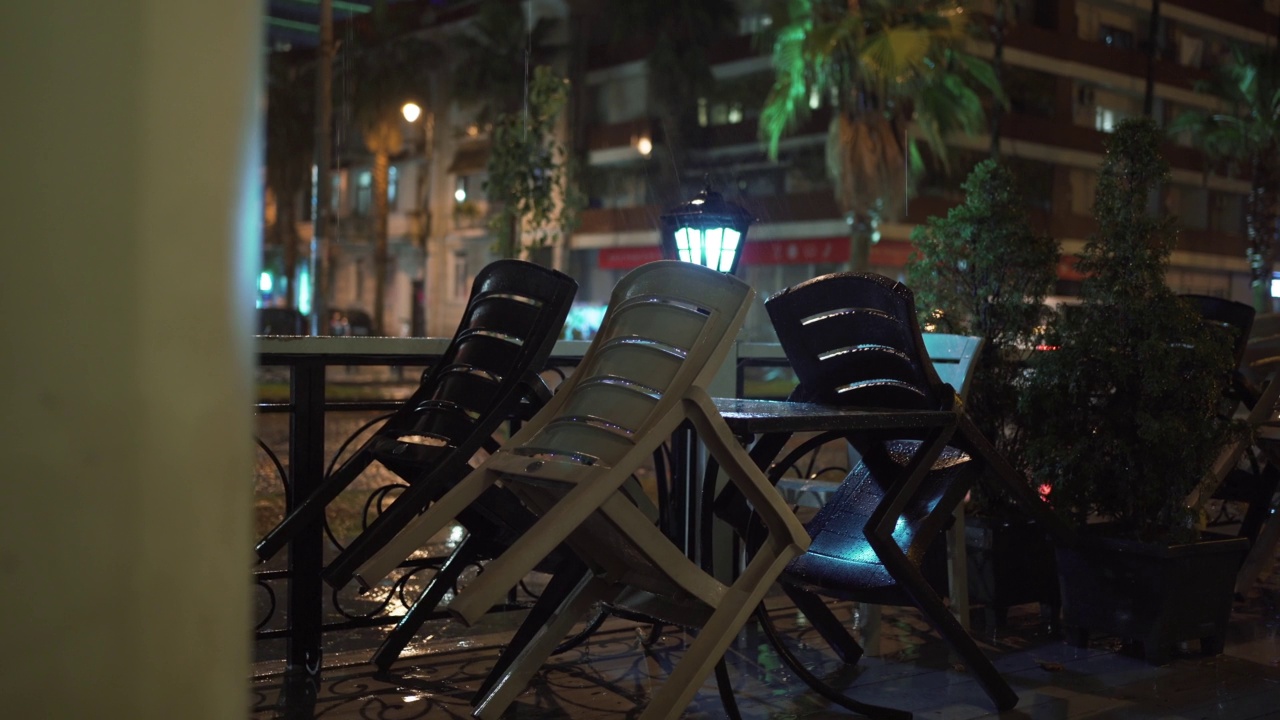 雨夜，咖啡馆露台上空荡荡的餐厅桌子。雨的季节视频素材