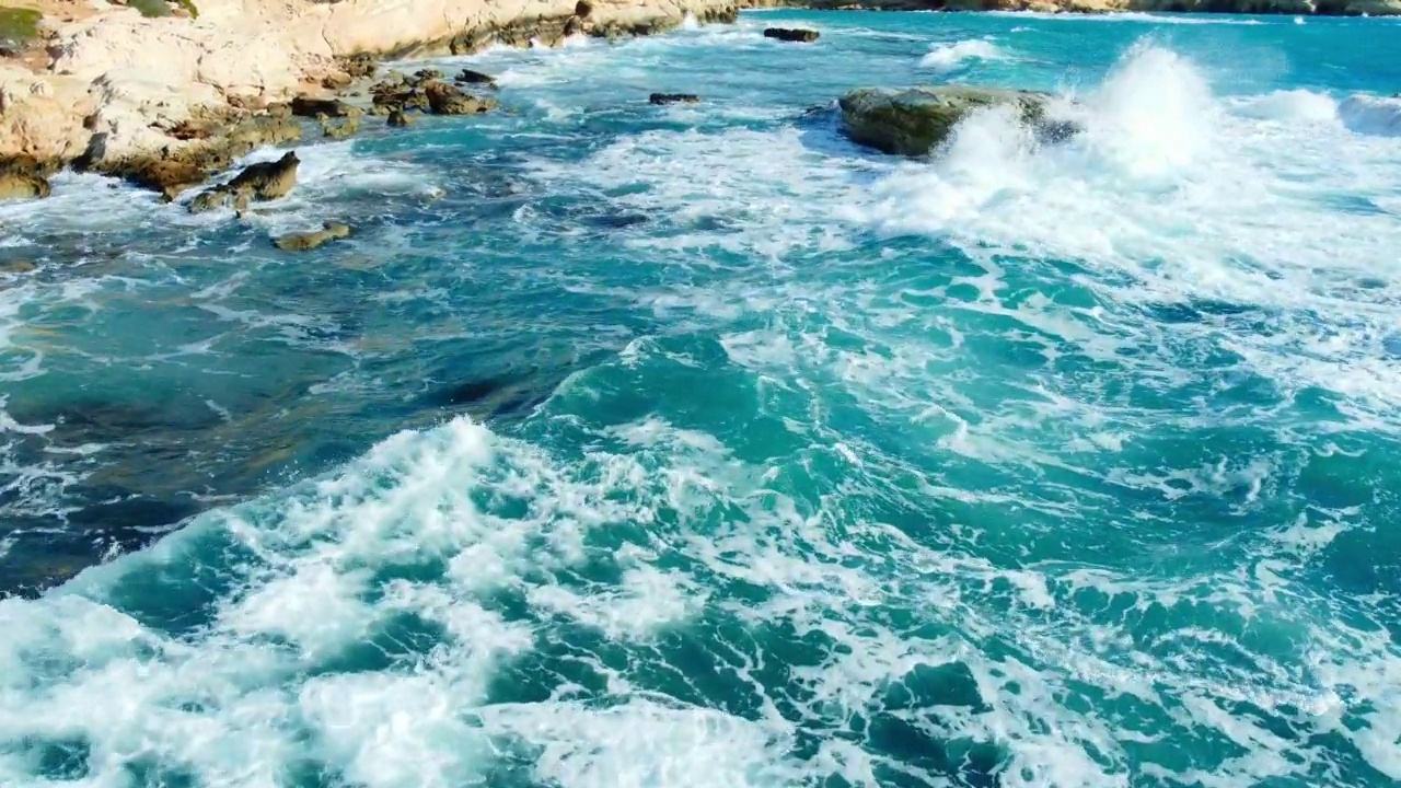 海岸线鸟瞰自然景观，碧蓝的海水与岩石海岸的波浪视频素材