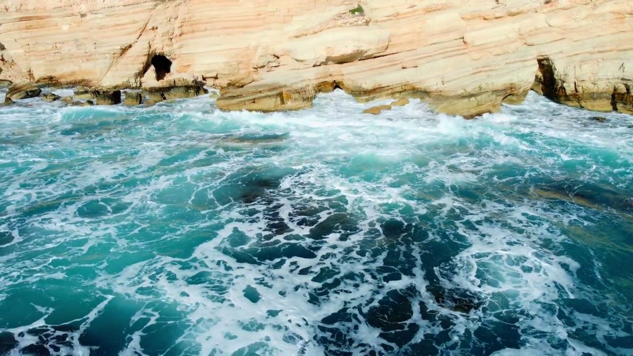 海岸线鸟瞰自然景观，碧蓝的海水与岩石海岸的波浪视频素材