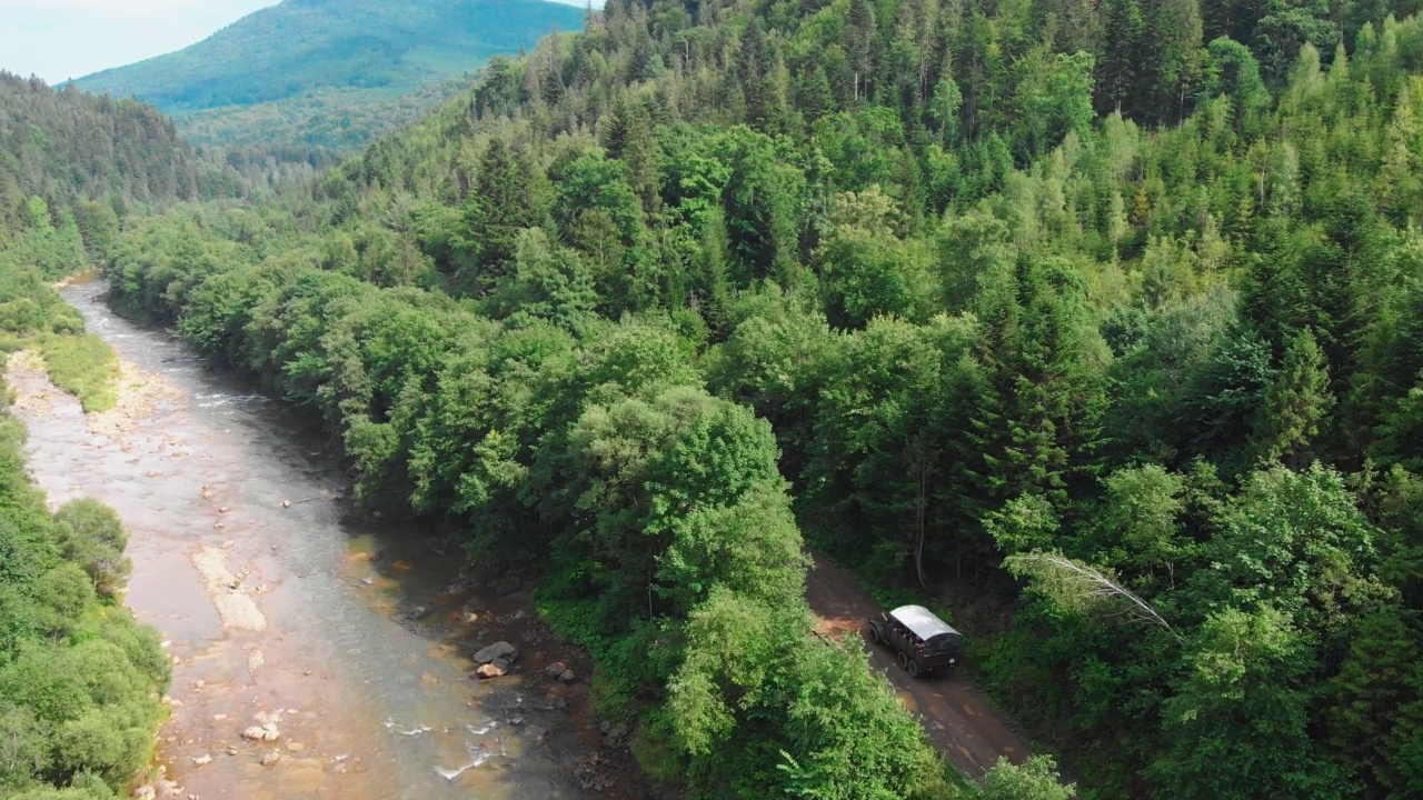 夏天去乌克兰喀尔巴阡山脉旅行。一辆大型旅游车在自然的山川绿林中航拍。卡车行驶在一条旅游线路的山路上视频素材