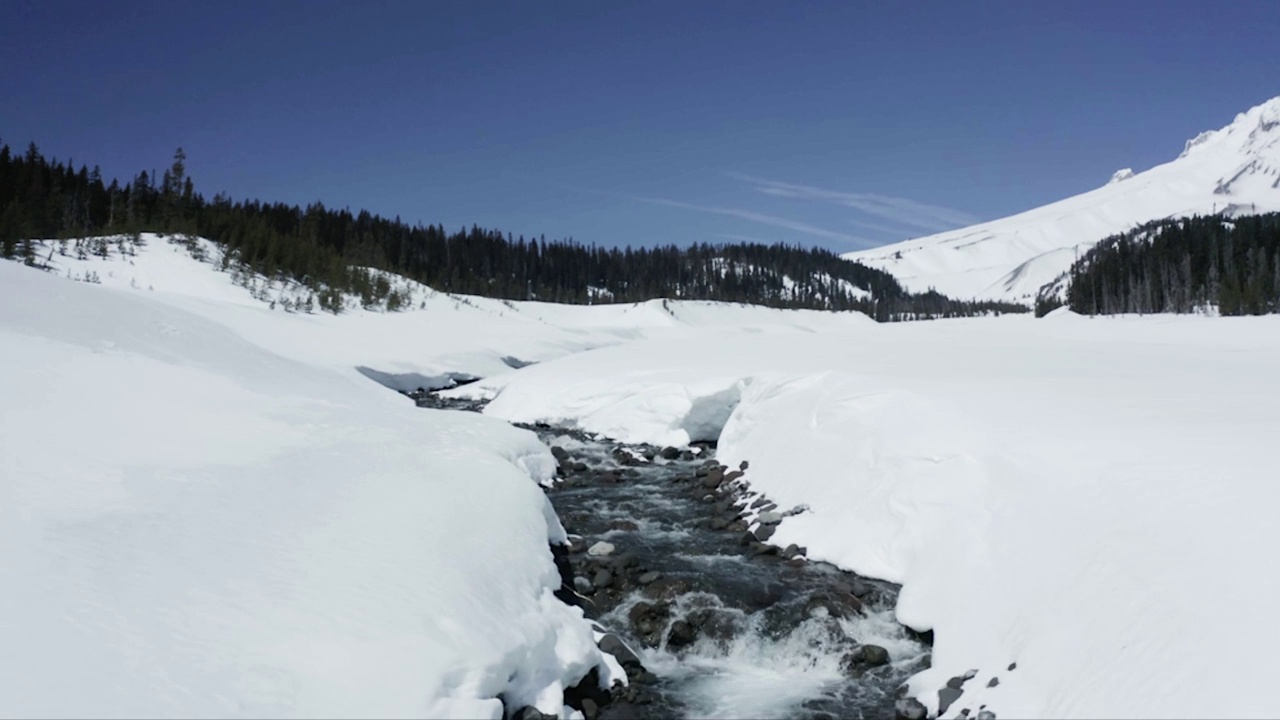 空中拍摄的河流被冰雪覆盖的落基山脉包围视频素材