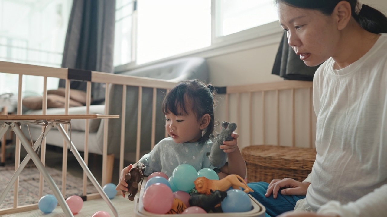 亚洲妈妈喜欢在家里陪女儿玩玩具，在家里过蒙氏教育视频素材