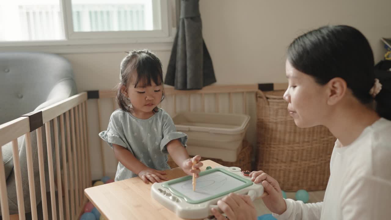 积极的情感亚洲女婴喜欢在家跟妈妈学画画蒙台梭利教育家庭生活理念视频素材