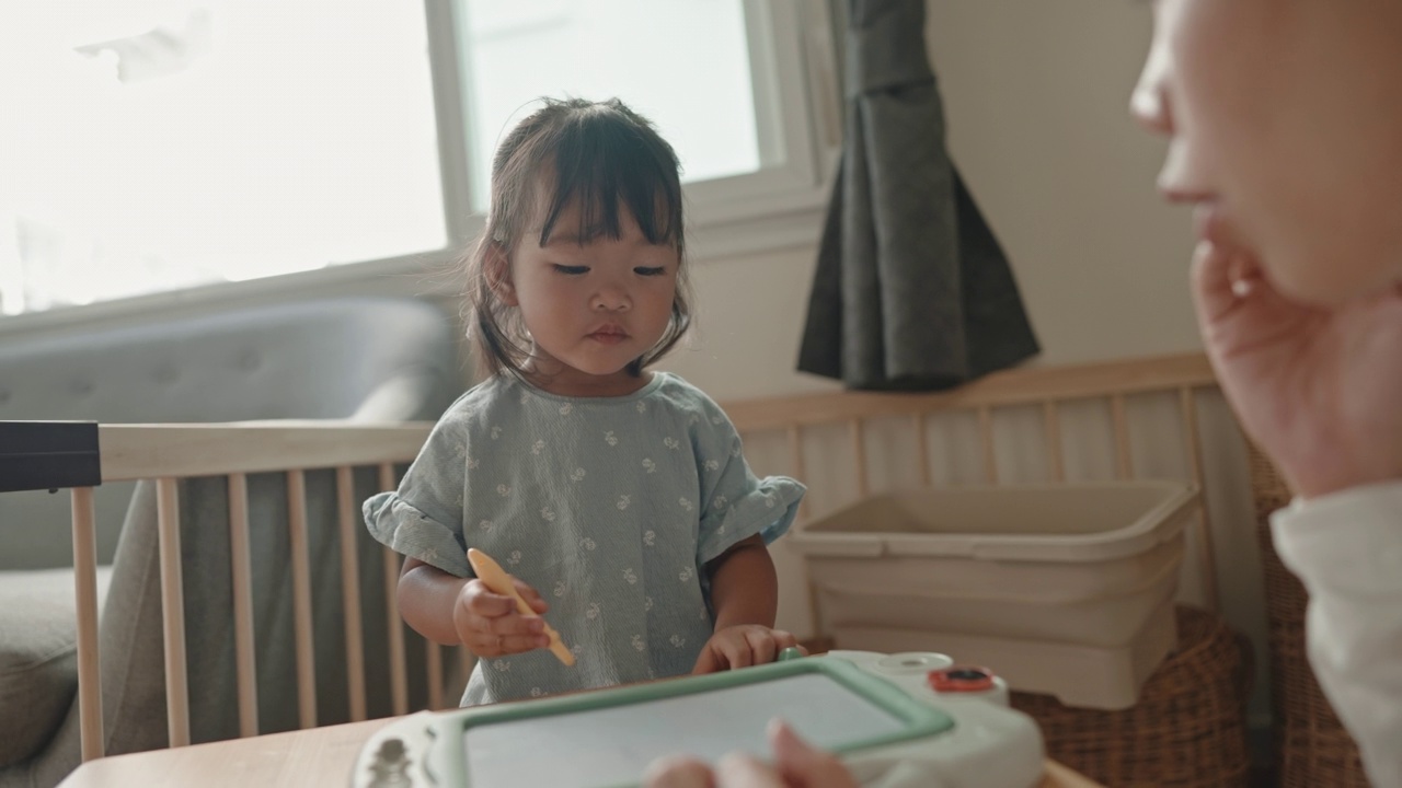 积极的情感亚洲女婴喜欢在家跟妈妈学画画蒙台梭利教育家庭生活理念视频素材