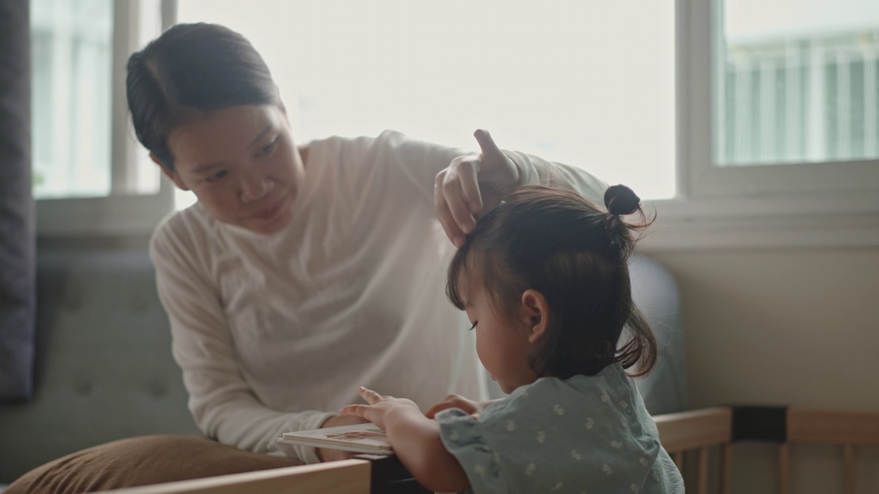 在家里，妈妈和女儿一起看图画书，讲故事。蒙台梭利家庭生活视频素材