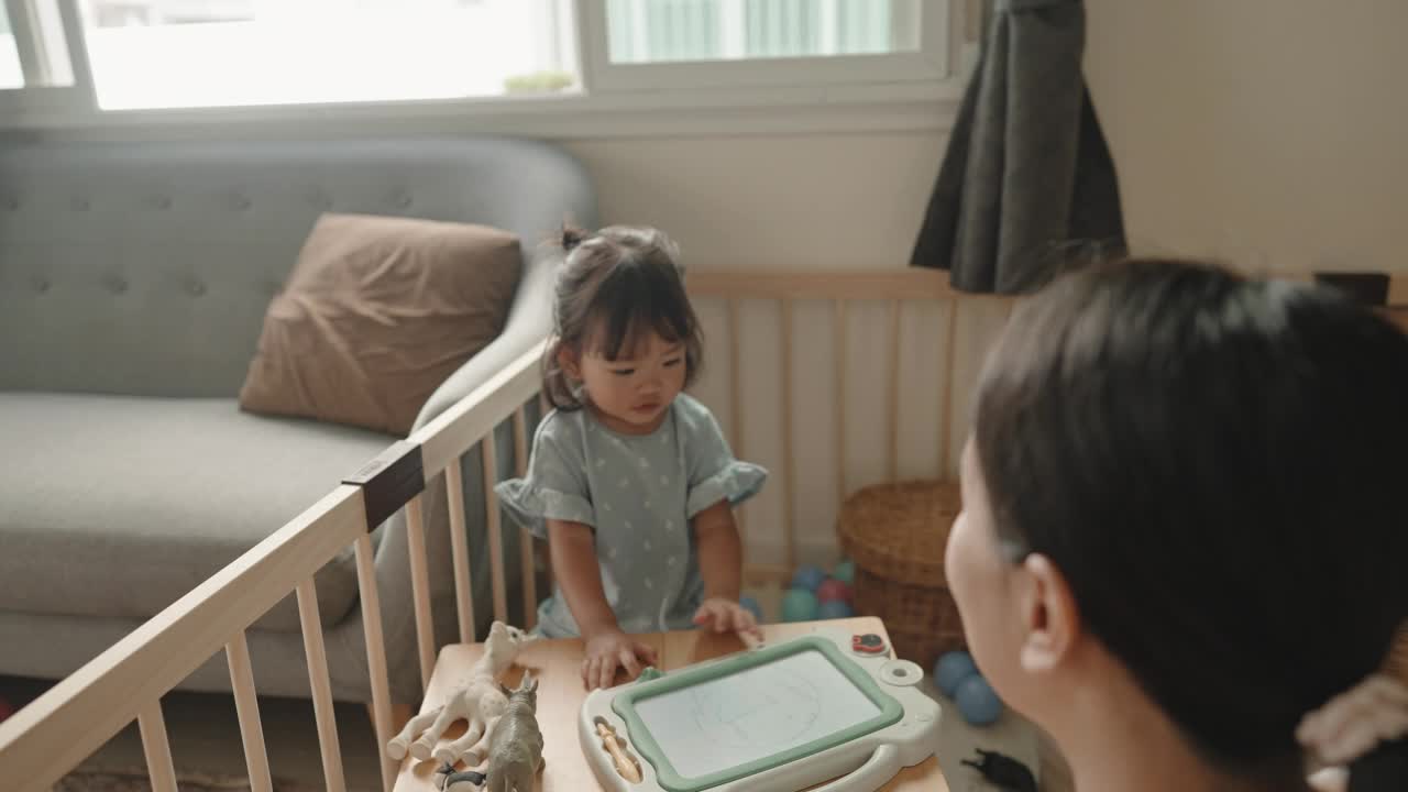 亚洲妈妈喜欢在家里陪女儿玩玩具，在家里过蒙氏教育视频素材