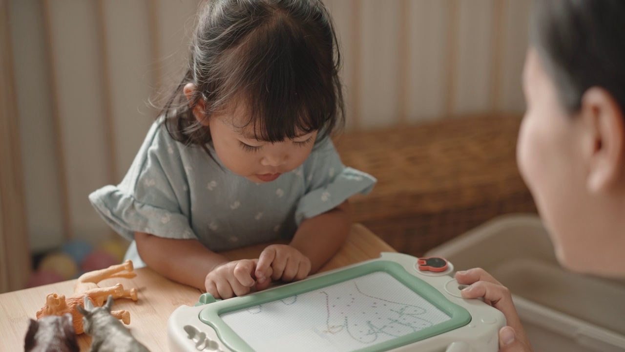 积极的情感亚洲女婴喜欢在家跟妈妈学画画蒙台梭利教育家庭生活理念视频素材