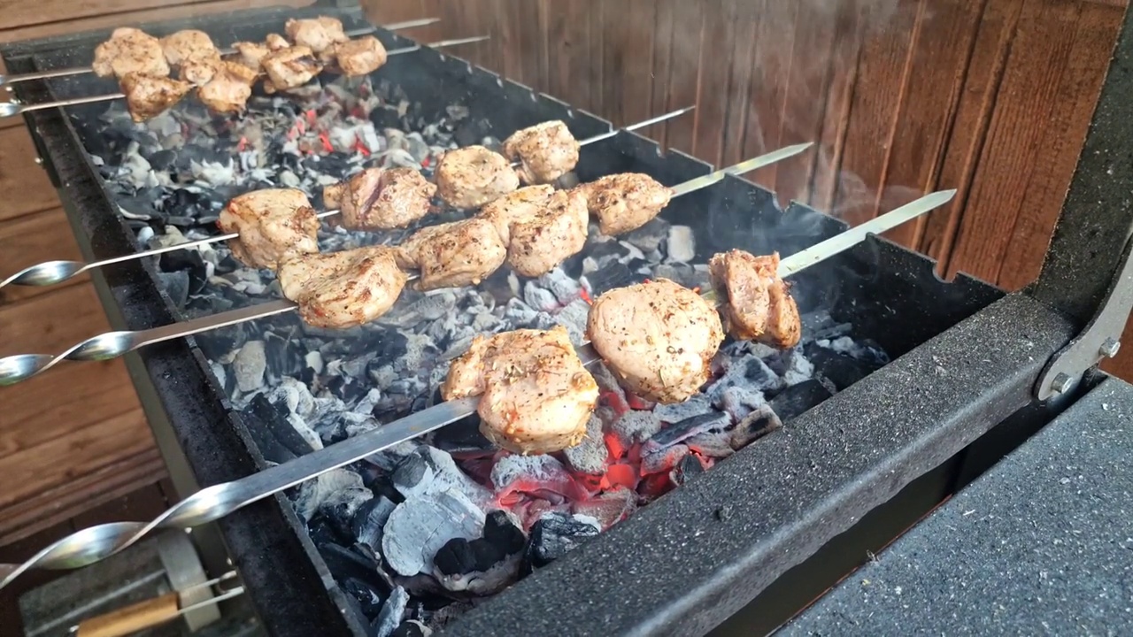 烤制:在金属烤架上用燃烧的木柴和烟烤烤肉的过程烤的肉。为野餐做饭。美味多汁，香气四溢的烤肉块。视频素材