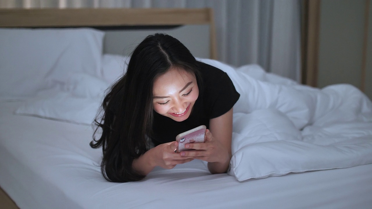 一名女子在晚上用手机在社交媒体应用程序上微笑视频素材