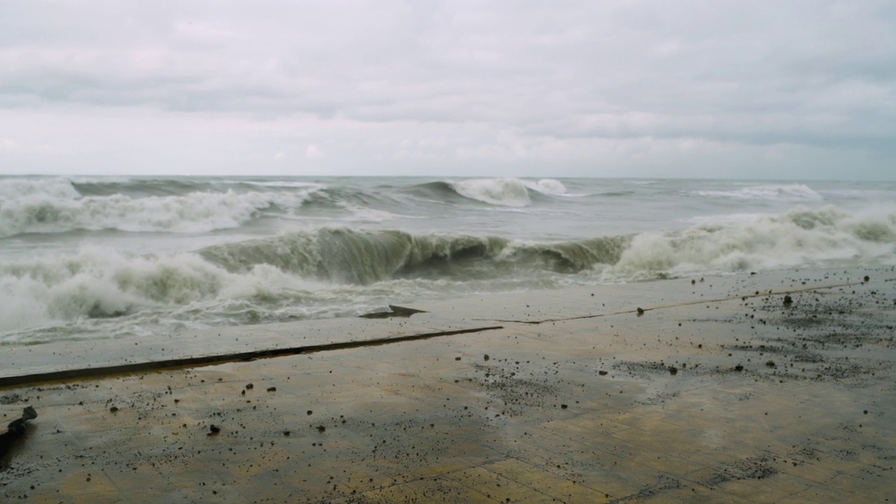 在极端的暴风雨天气中，海浪冲击着被摧毁的道路和海岸线视频素材