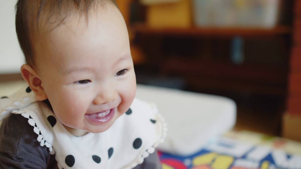 肖像接近快乐可爱可爱的亚洲婴儿蹒跚学步的孩子笑着快乐的脸，女婴享受兴奋的表情情绪无忧无虑，而躺在家里的客厅视频素材