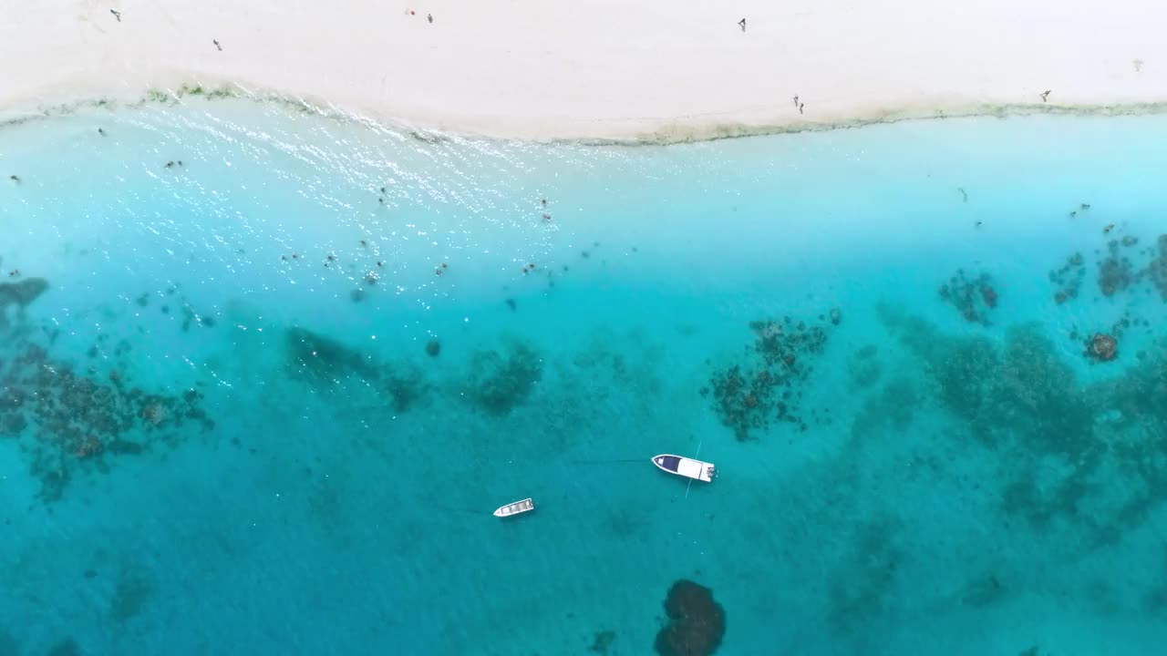 在夏天阳光明媚的一天，船和游艇在透明的蓝色水域的鸟瞰图。从无人驾驶飞机俯瞰海上摩托艇，海浪，白色沙滩。印度洋上的非洲桑给巴尔岛。景观视频素材