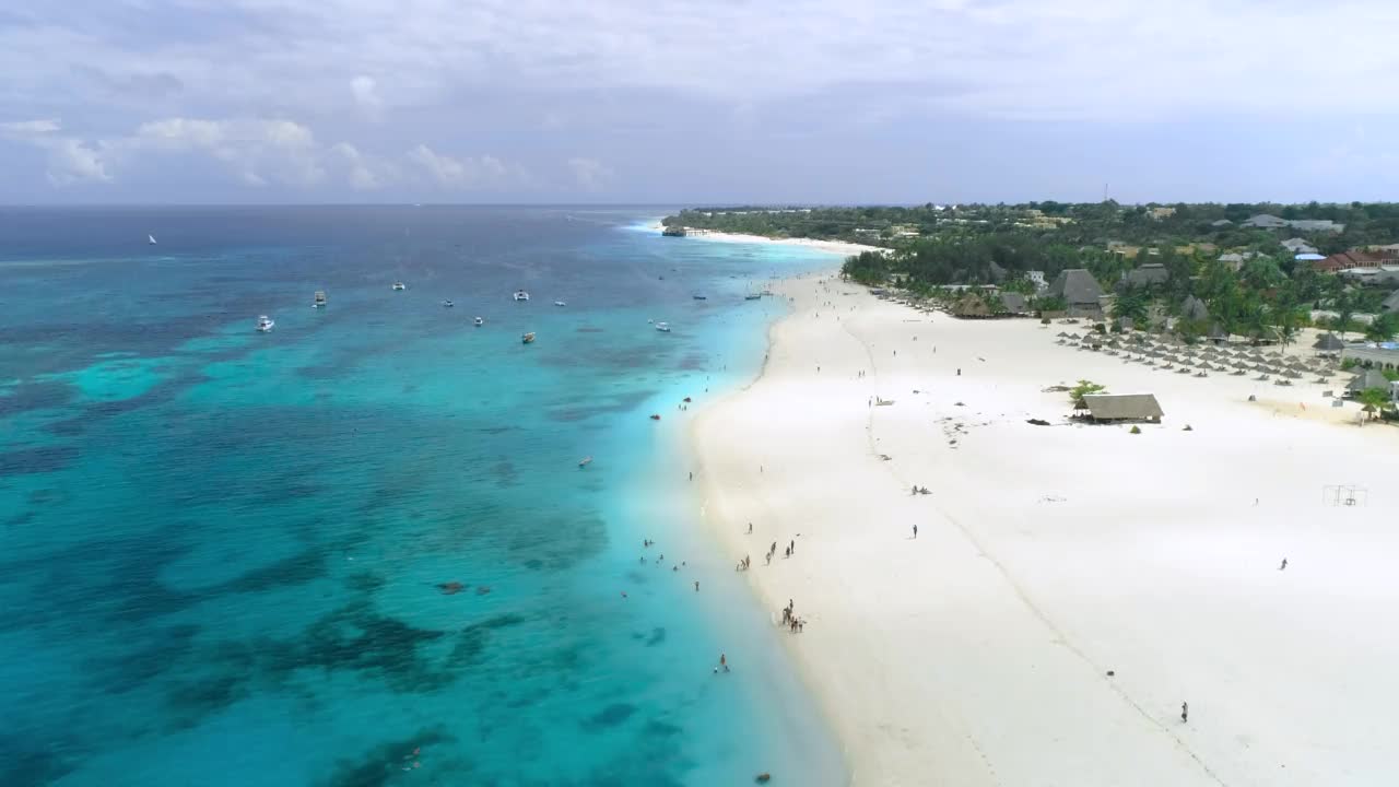 蓝色的海洋，沙滩，游泳的人，船和游艇在透明的海水在夏天的晴天鸟瞰。俯视大海，白沙，棕榈树。热带。桑给巴尔岛,非洲视频素材