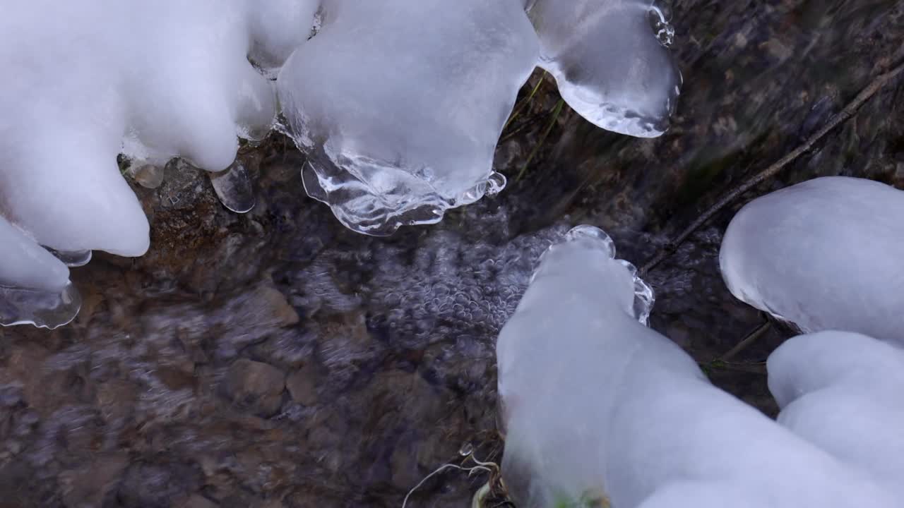 在冬天的小溪边，冰封的树枝和树叶变成了雪花视频素材