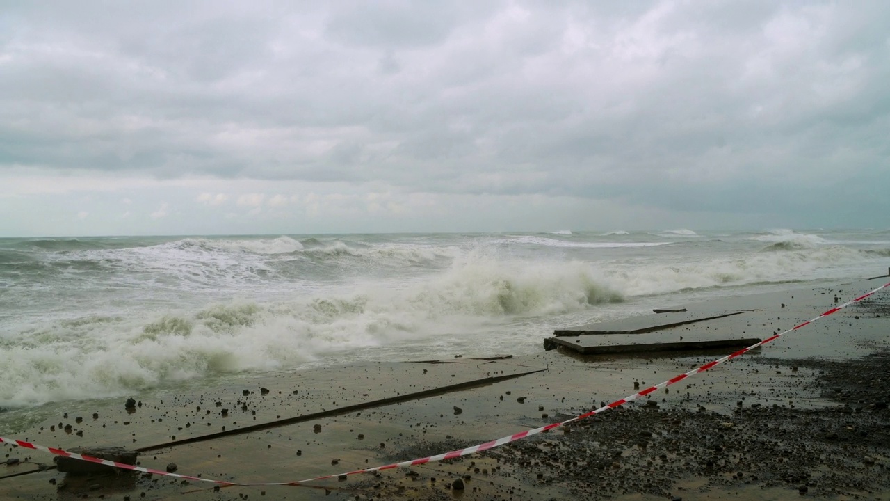 在极端的暴风雨天气中，海浪冲击着被摧毁的道路和海岸线视频素材