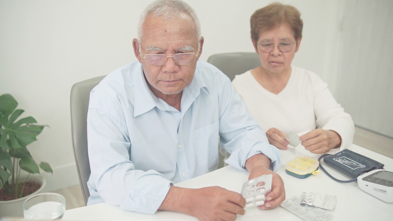 远程医疗概念，亚洲老年夫妇在家里的客厅用笔记本电脑通过视频电话听医生的建议。视频素材