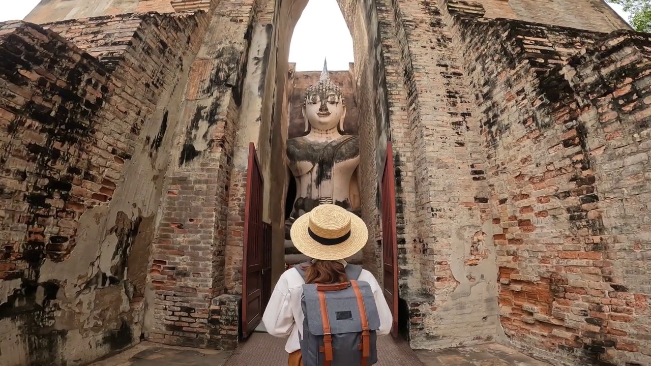 一名女游客走进了位于围城外素可泰历史公园北区的Wat Si Chum寺的屋顶建筑。视频素材