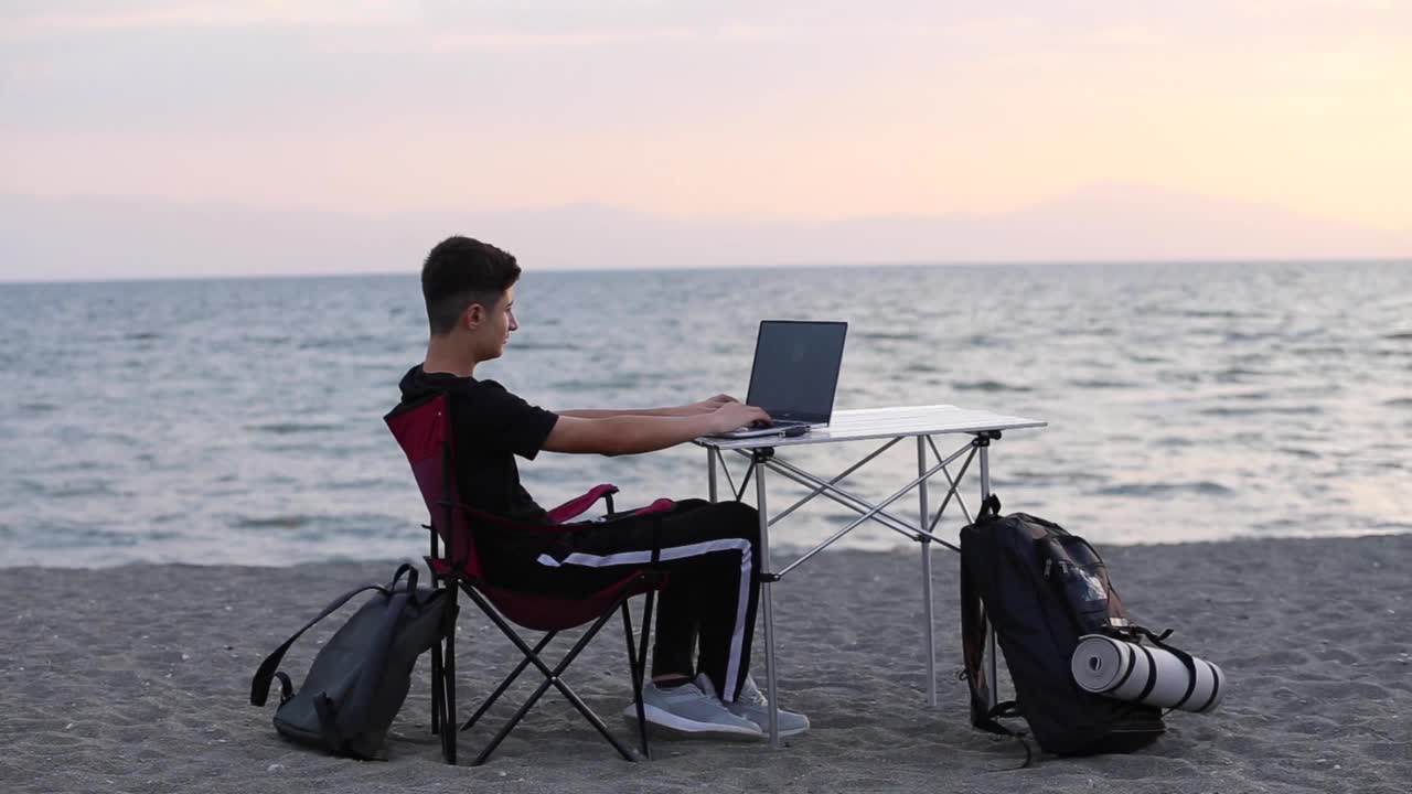 年轻人在海滩上摆弄电脑。视频素材