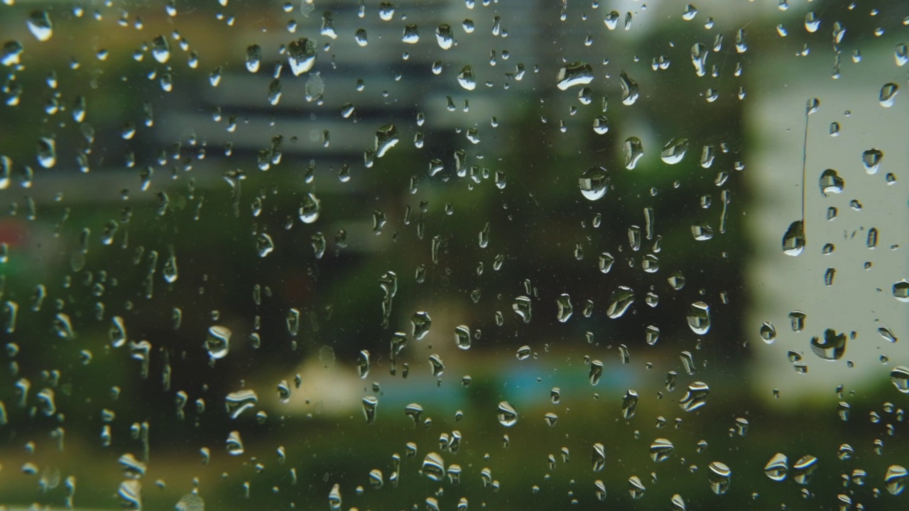 雨滴打在窗玻璃上。湿窗中城市的剪影。视频素材