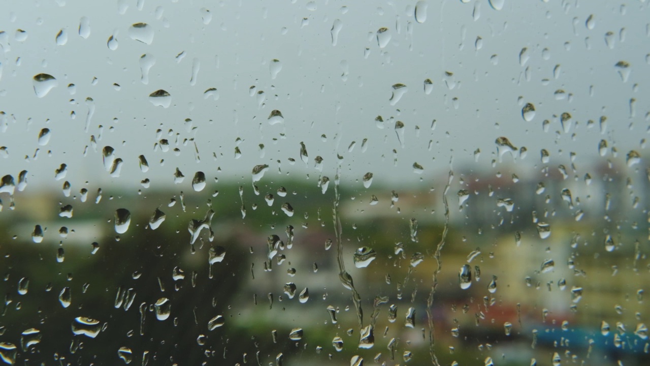 雨滴打在窗玻璃上。湿窗中城市的剪影。视频素材