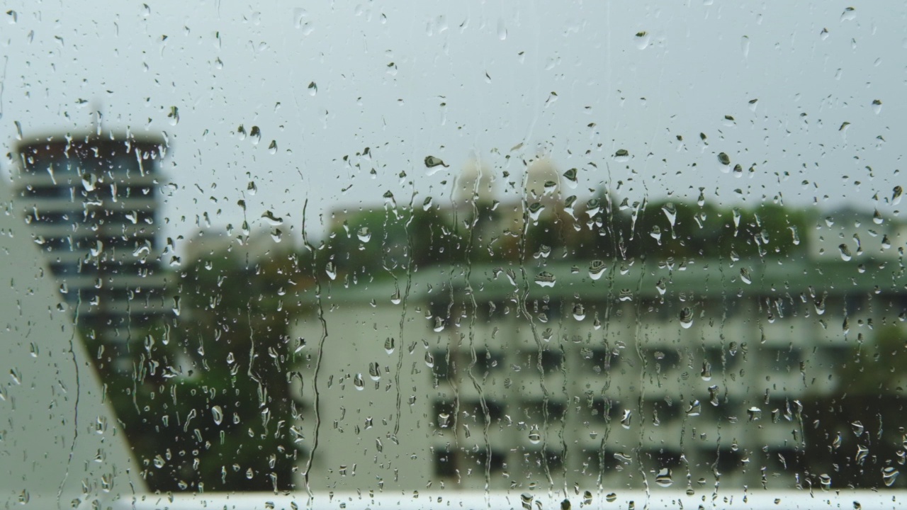 雨滴打在窗玻璃上。湿窗中城市的剪影。视频素材