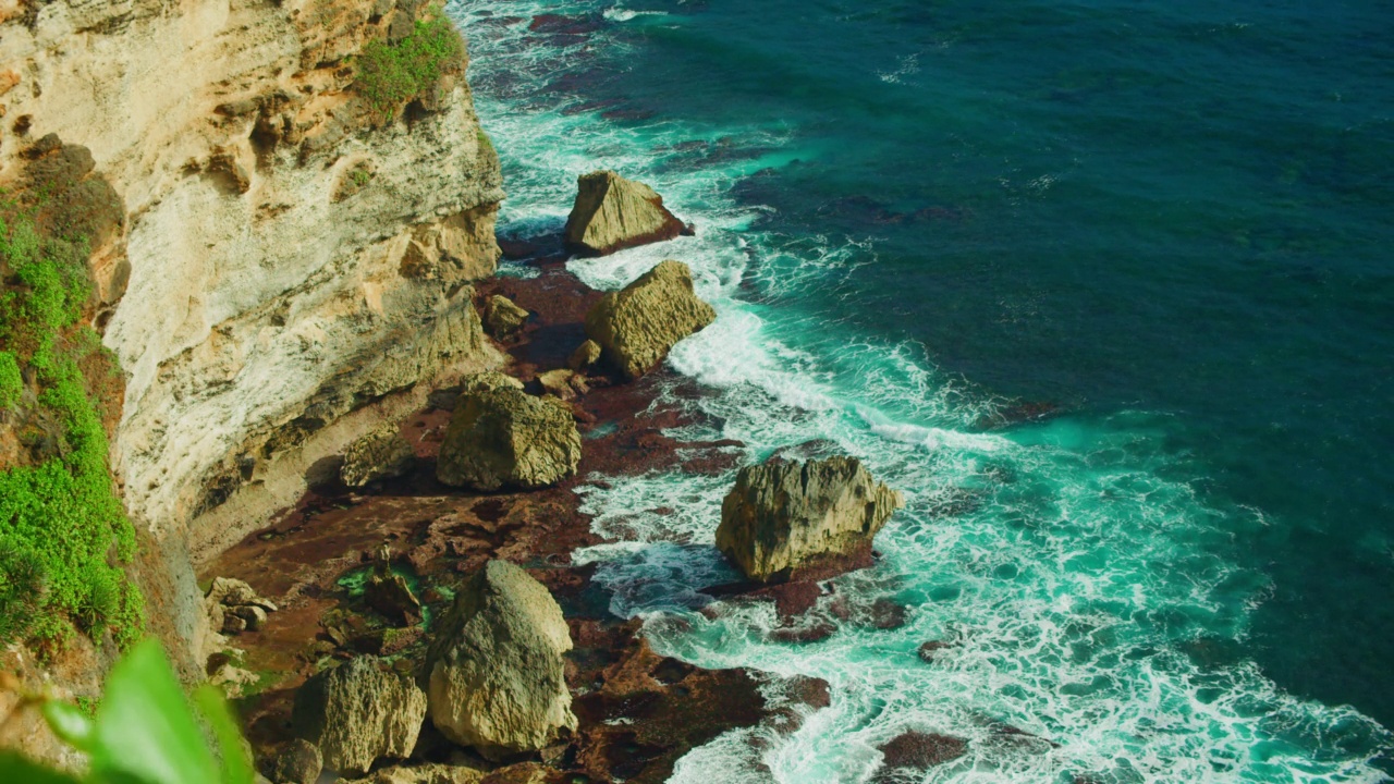 石崖绿松石深海岩石海滩浪花泡沫。热带景观。静态自顶向下视图。印度尼西亚巴厘岛乌鲁瓦图的自然风光。视频素材