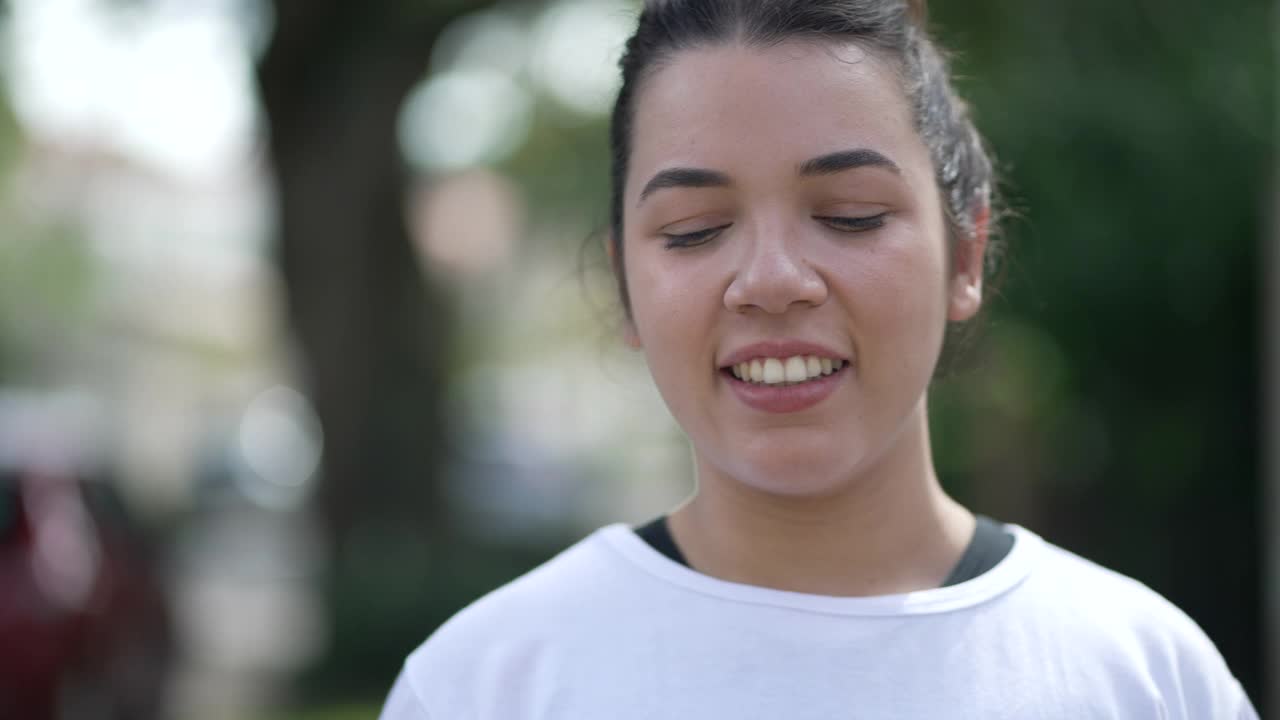 一个沉思的西班牙女孩走在城市的街道上。20多岁的年轻拉丁女人在沉思中散步视频素材