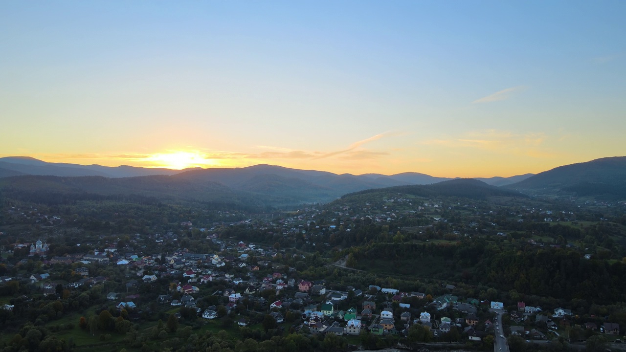 秋天日出时，明亮多雾的早晨鸟瞰图，在黑暗的山峰和山林之间的小乡村房屋上。黎明时分野生林地的美丽景色视频素材