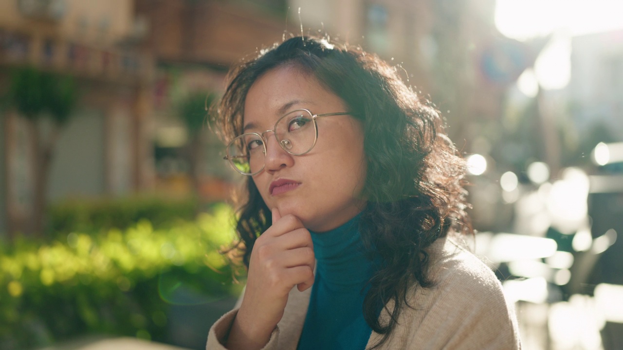 年轻的中国女子站在街上，脸上带着怀疑的表情视频素材