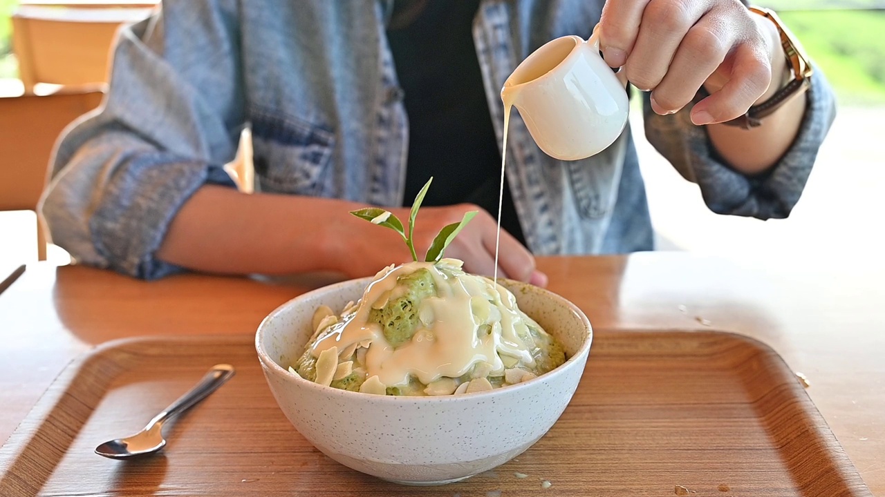 有人在吃饭前把炼乳倒在抹茶冰糖上。冰糕是韩国的传统甜品。视频素材