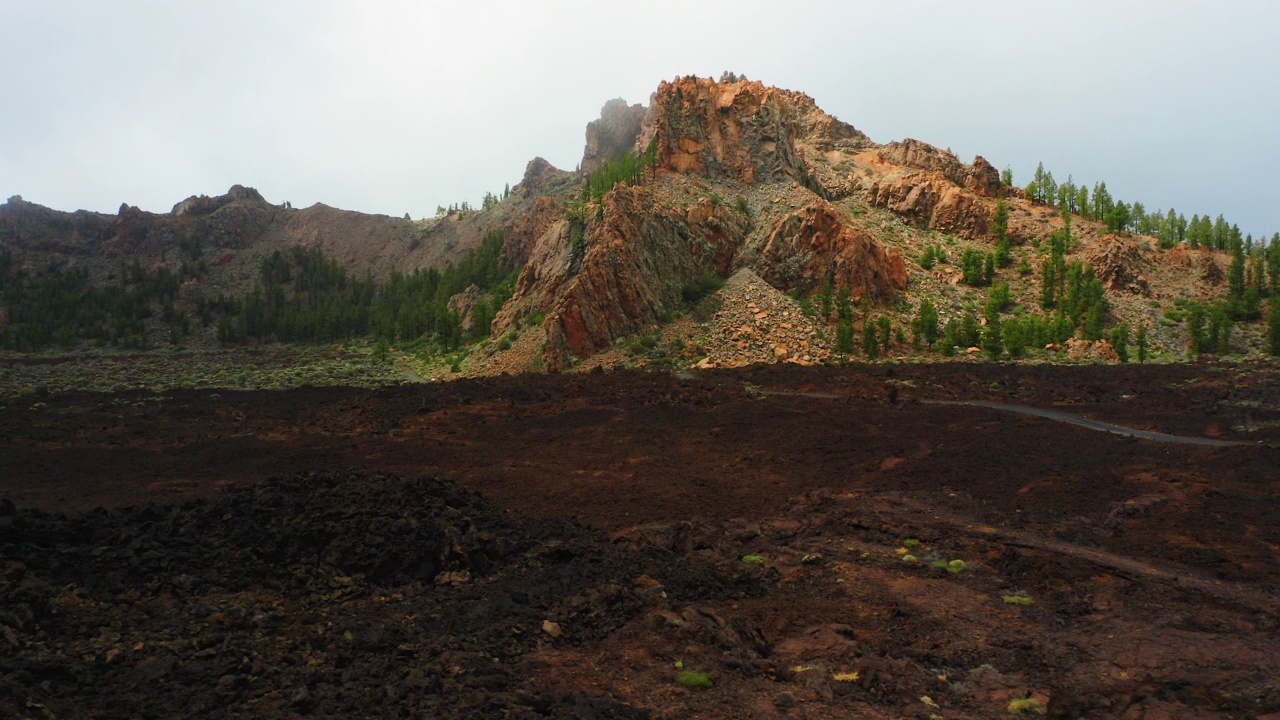 贫瘠的熔岩火山多云的天气，薄雾吹过悬崖。沙漠景观中的道路航拍镜头。美丽的大自然。松林。夜夜云。公园泰德。视频素材