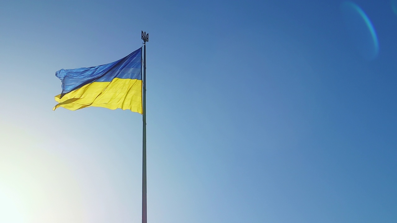 拂晓时分，晴空万里，乌克兰国旗迎风飘扬。乌克兰的国家象征是蓝色和黄色。标志环与详细的织物纹理视频素材