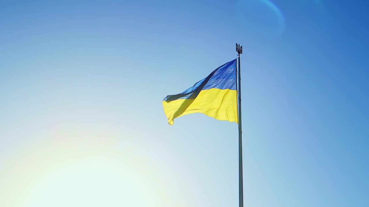 拂晓时分，晴空万里，乌克兰国旗迎风飘扬。乌克兰的国家象征是蓝色和黄色。标志环与详细的织物纹理视频素材