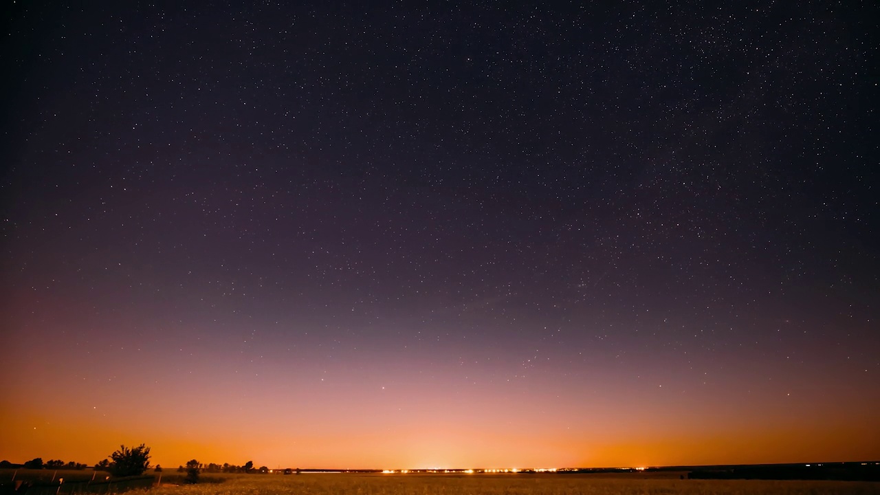 夏季田野草地上的自然夜星空。发光的星星和日落日出的光在景观。视频素材