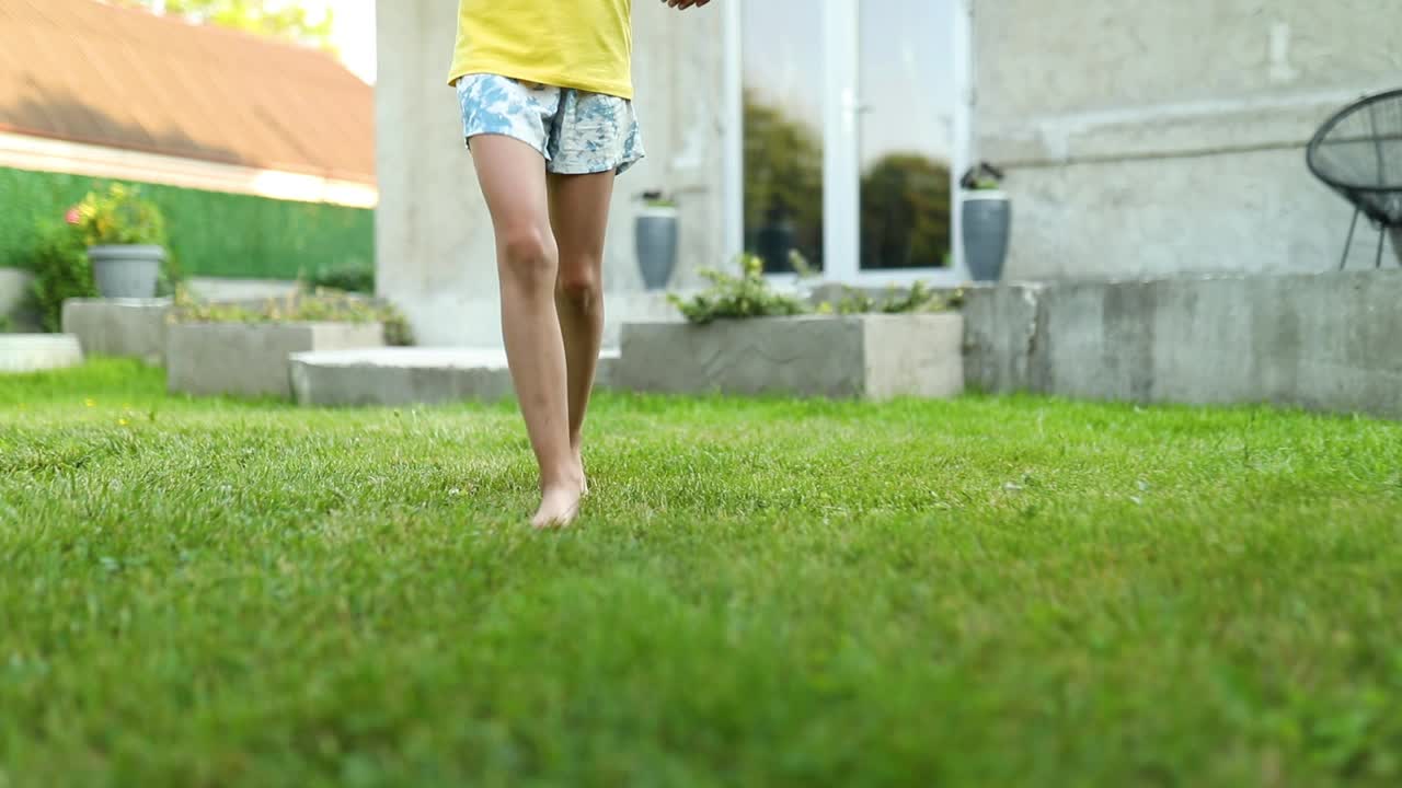 慢镜头未知女孩赤脚跑在绿色草地在夏天。视频素材