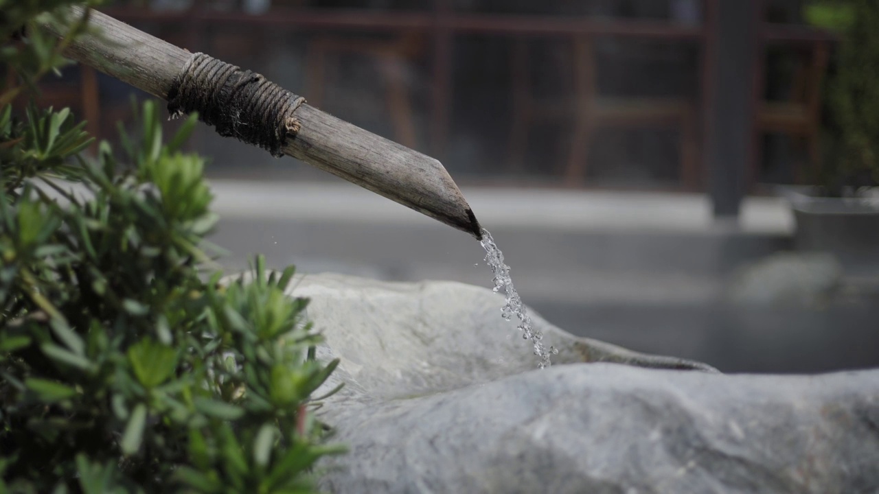 水从竹管制成的水管中流入泉水。视频素材