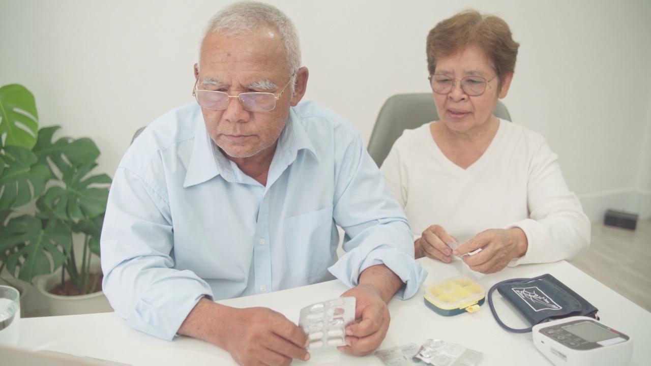 远程医疗概念，亚洲老年夫妇在家里的客厅用笔记本电脑通过视频电话听医生的建议。视频素材