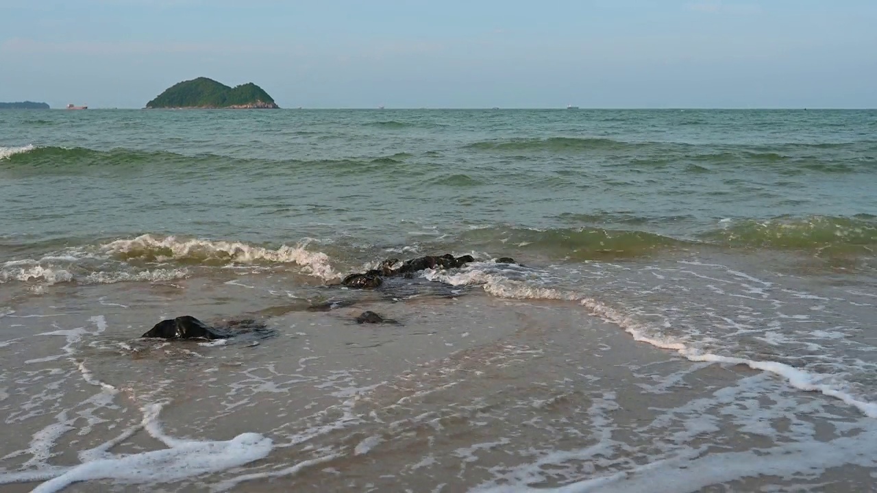 美丽的风景，海浪在沙滩上奔跑，以岛屿为背景。视频素材