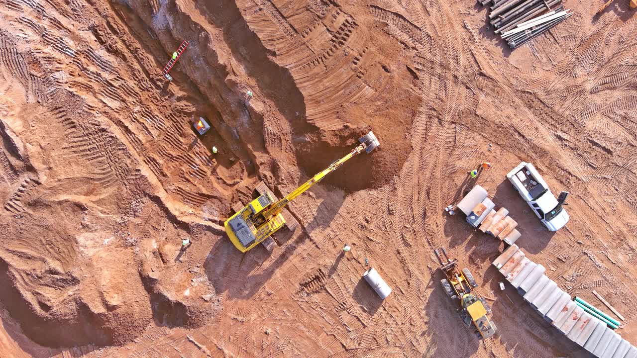 挖掘机在建筑工地挖坑，以便连接下水道和铺设地下雨水下水道管道。视频素材