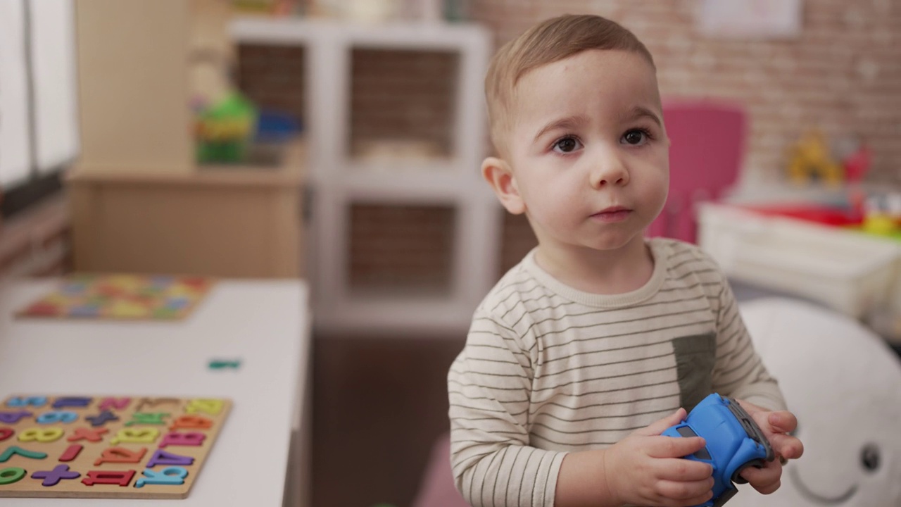 可爱的幼儿在幼儿园的桌子上玩汽车玩具视频素材