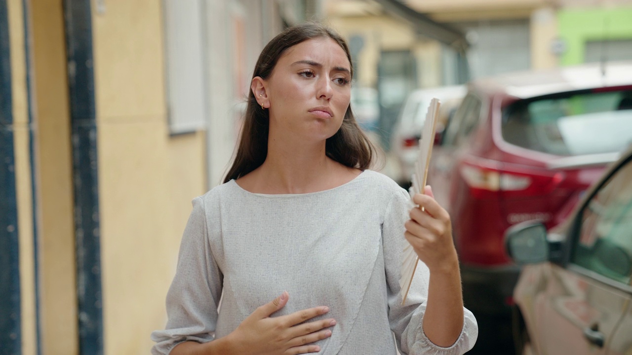 年轻美丽的西班牙女人用手扇痛苦的热在街上视频素材