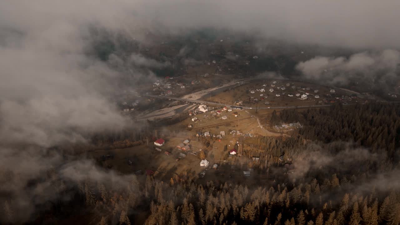 时间流逝的鸟瞰图雾海漂浮翻滚在村庄在山谷在日出黄金时间黑暗森林前景时间流逝。无人机飞越云雾缭绕的山林视频素材