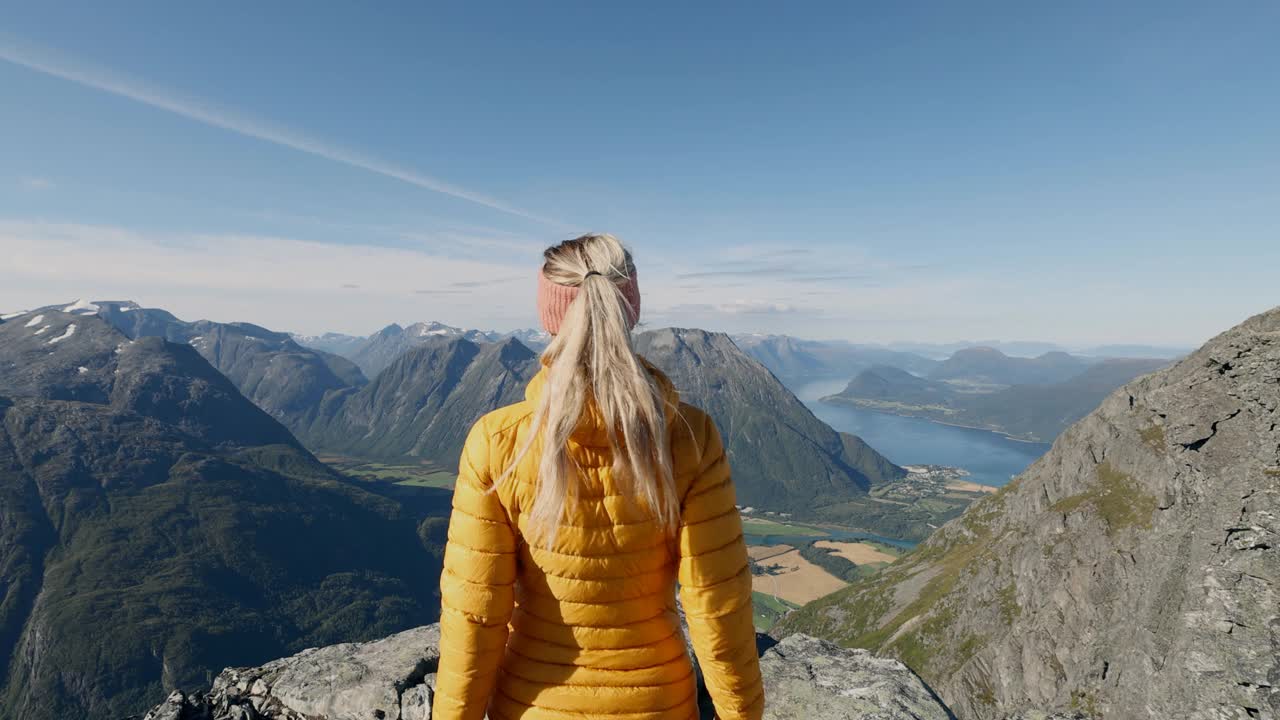 在挪威徒步旅行的女子在山顶张开双臂。视频素材