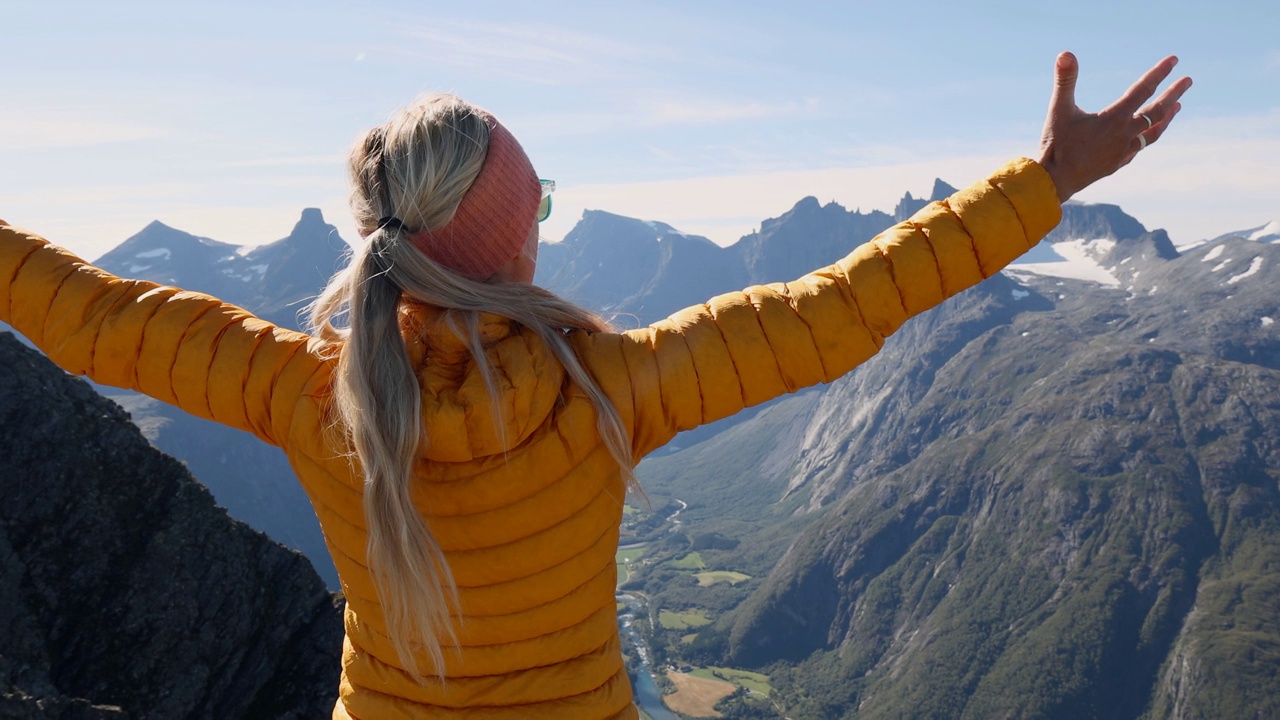 在挪威徒步旅行的女子在山顶张开双臂。视频素材