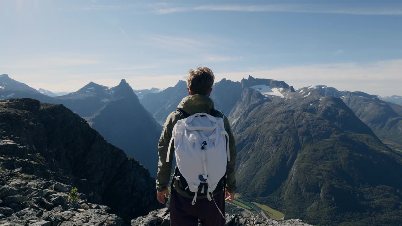 挪威徒步旅行的男子在山顶张开双臂。壮观的河流和峡湾景色视频素材