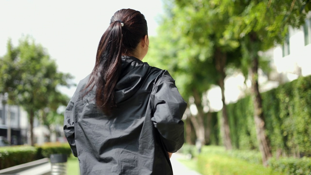 漂亮迷人的女人穿着运动服在公园里跑步。健康的女人慢跑在户外在村庄。在早上锻炼。健康积极的生活方式理念。视频素材